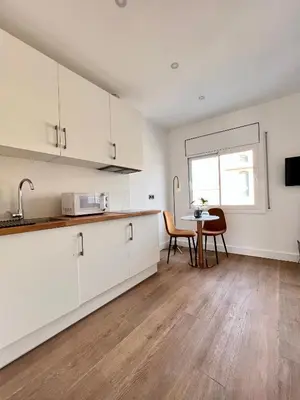 a kitchen with white cabinets and a table and a window at Crysoyle Apartment Barcelona Next to Camp Nou in Hospitalet de Llobregat