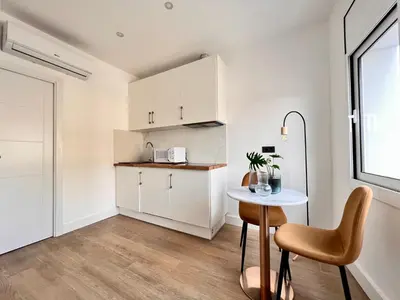 a kitchen with white cabinets and a table and a window at Crysoyle Apartment Barcelona Next to Camp Nou in Hospitalet de Llobregat
