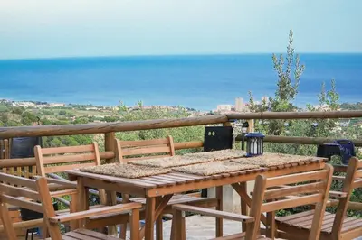 a wooden table and chairs on a balcony with the ocean at AAA View Private Terrace Outdoor Heated Hot Tub Family Fun in Badalona