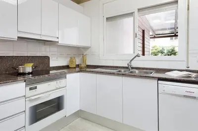 a white kitchen with white cabinets and a sink at Stay U-nique House Torre Damians in Barcelona