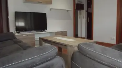a living room with two chairs and a table and a television at Apartamentos Atlas Terrassa I in Terrassa
