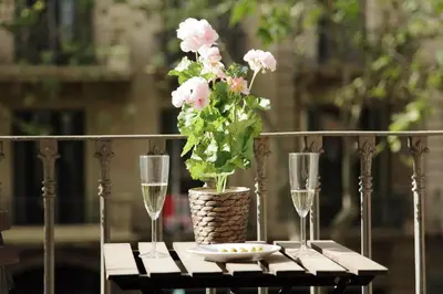 a table with two glasses and a vase with pink flowers at Rafael Music Palace apartment in Barcelona
