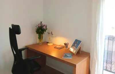 a wooden desk with a vase of flowers on it at Comfortable apartment. Very central and quiet. in Barcelona