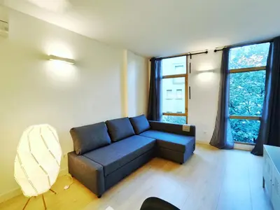 a living room with a blue couch and two windows at Moderno Apartamento en Terrassa Centro in Terrassa