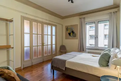 a bedroom with a bed and two windows at Canela Homes BARCELONA MODERNISTA in Barcelona