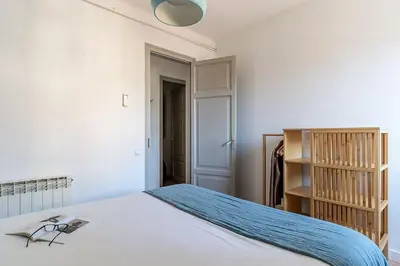 a bedroom with a white bed and a book shelf at Canela Homes BARCELONA BAILÉN in Barcelona