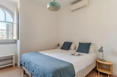 a white bed with blue pillows in a room at Canela Homes BARCELONA BAILÉN in Barcelona