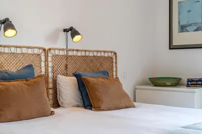 a bed with brown and blue pillows on it at Canela Homes COSTA CASTELLDEFELS in Castelldefels