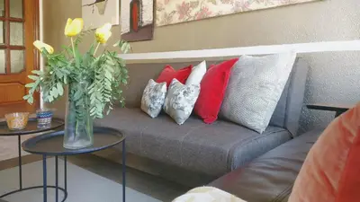 a couch with pillows and a vase with flowers on it at Auditori Barcelona in Barcelona