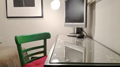 a glass table with a television and a green chair at Auditori Barcelona in Barcelona