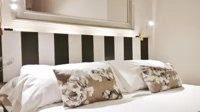 a bed with white pillows and a black and white striped wall at Auditori Barcelona in Barcelona