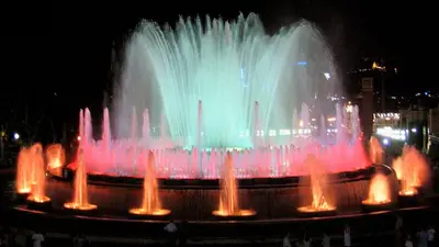 a large fountain with colorful water jets in a city at Fira Suites in Barcelona