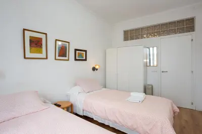 two beds in a room with white walls at Fira Suites in Barcelona