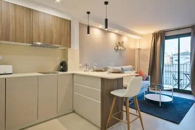 a kitchen with white cabinets and a table and chairs at YOUR HOME - Camp Nou Apartment in Hospitalet de Llobregat