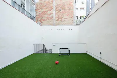 a soccer ball on a green field in an empty building at YOUR HOME - Camp Nou Apartment in Hospitalet de Llobregat
