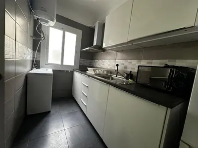 a kitchen with white cabinets and a sink and a window at Apartments near Ramblas - Only for stays over 32 days in Barcelona