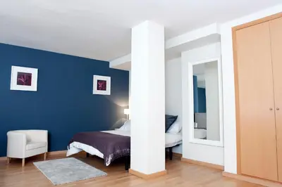 a bedroom with a bed and a blue wall at Fira Duplex in Hospitalet de Llobregat