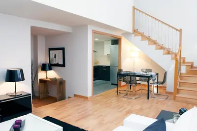 a living room with a table and a staircase at Fira Duplex in Hospitalet de Llobregat