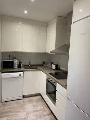 a kitchen with white appliances and white cabinets at Nice Apartment 2 Bedrooms Well Connected in Cornellà de Llobregat