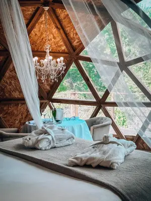 a bed in a room with a table and a chandelier at Bubble Suites in Canyelles