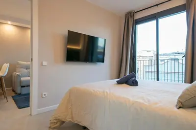 a bedroom with a bed with a tv on the wall at bonito piso cerca del campo de futbol de barcelona in Hospitalet de Llobregat