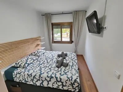 a small bedroom with a bed and a television at Family apartment Besos 2 in Sant Adria de Besos