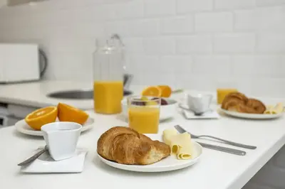 a table with plates of breakfast foods and orange juice at Canela Homes BARCELONA FONTANA in Barcelona