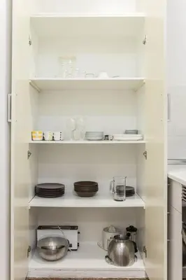 a kitchen with white shelves with plates and dishes at Canela Homes BARCELONA FONTANA in Barcelona