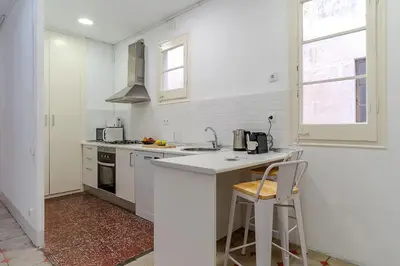 a white kitchen with a counter and two stools at Canela Homes BARCELONA FONTANA in Barcelona