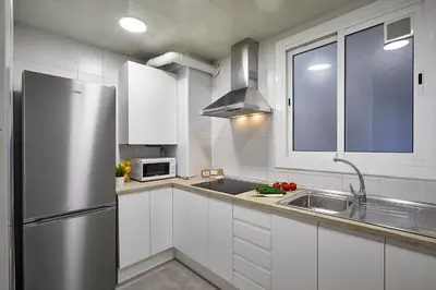 a kitchen with white cabinets and a stainless steel refrigerator at BBarcelona Central Eixample Flat in Barcelona