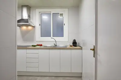 a white kitchen with a sink and a window at BBarcelona Central Eixample Flat in Barcelona