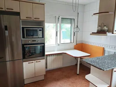 a kitchen with a counter and a table in it at Casa con jardín y piscina privada. in Santa Eulalia de Ronsaná