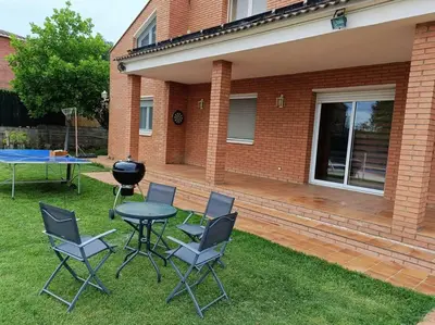 a patio with a table and chairs and a grill at Casa con jardín y piscina privada. in Santa Eulalia de Ronsaná