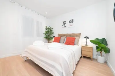 a white bedroom with a large bed with red pillows at Soler Apartments in Sant Adria de Besos