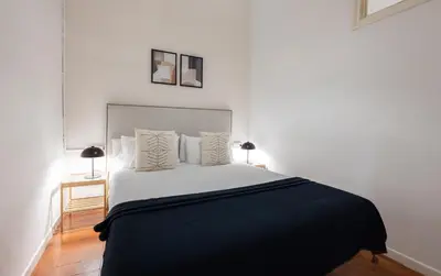 a bedroom with a bed with a black blanket and two lamps at Stay U-nique Apartments Granados in Barcelona