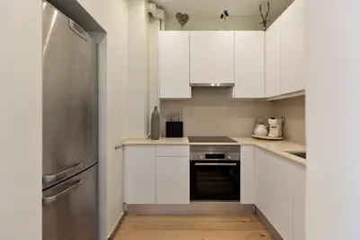 a kitchen with white cabinets and a stainless steel refrigerator at Enjoy Apartments Donna in Barcelona