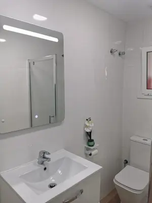 a white bathroom with a sink and a toilet at Ático in Terrassa