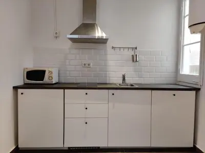 a kitchen with white cabinets and a microwave at Family apartment Gracia in Barcelona