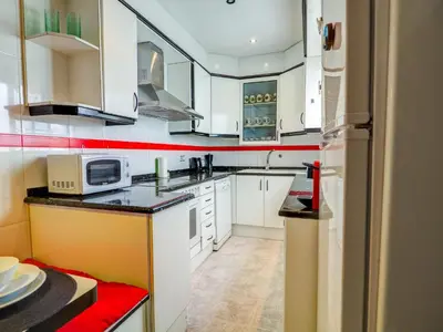 a kitchen with white cabinets and a microwave at Sea and Sand Penthouse by Hello Homes Sitges in Sitges
