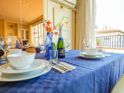 a blue table with plates and wine glasses on it at Sea and Sand Penthouse by Hello Homes Sitges in Sitges