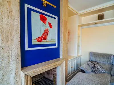 a room with a fireplace with a painting of a woman at Sea and Sand Penthouse by Hello Homes Sitges in Sitges