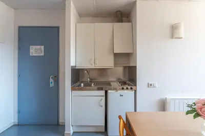 a kitchen with white cabinets and a sink and a table at Residencia Universitaria Resa Lesseps in Barcelona