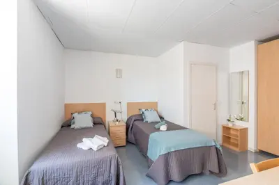 two beds in a room with white walls at Residencia Universitaria Resa Lesseps in Barcelona
