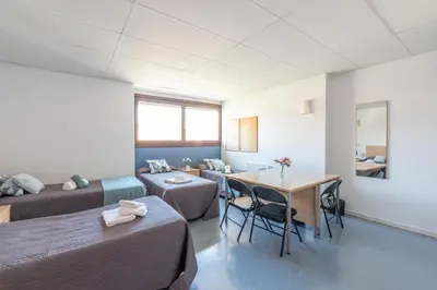 a room with two beds and a table and a couch at Residencia Universitaria Resa Lesseps in Barcelona