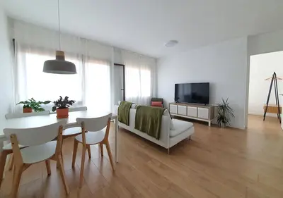 a living room with a table and a couch and a television at Acojedor piso cerca del metro in Cornellà de Llobregat
