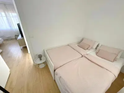 a white bed with pink pillows in a room at Acojedor piso cerca del metro in Cornellà de Llobregat