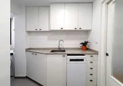a white kitchen with a sink and white cabinets at Acojedor piso cerca del metro in Cornellà de Llobregat