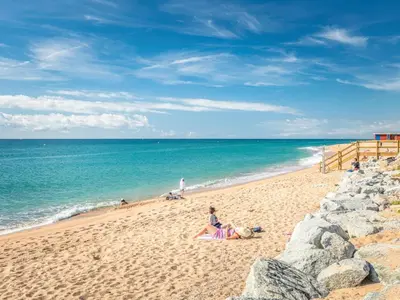 a group of people sitting on the beach at Apartamento con vistas al mar y piscina in Pineda de Mar