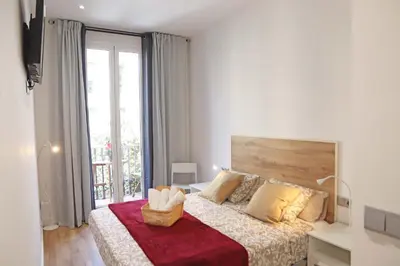 a bedroom with a large bed and a large window at Hostal Gràcia in Barcelona