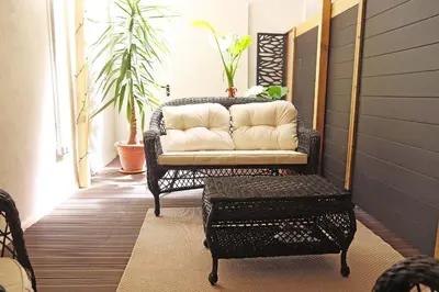 a wicker chair with a couch on a porch at Hostal Gràcia in Barcelona
